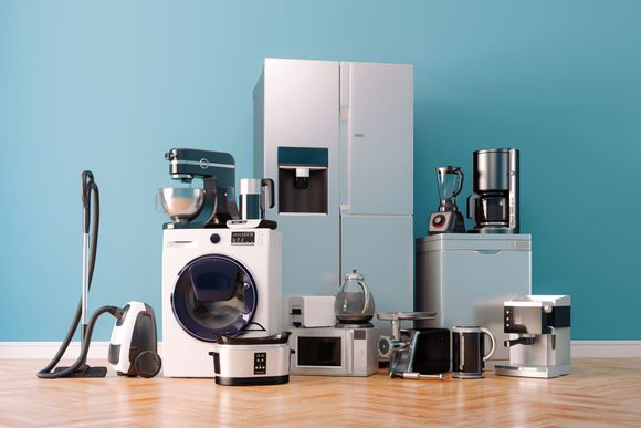 Assortment of modern home appliances against a blue wall, including a refrigerator, washing machine, and coffee maker.