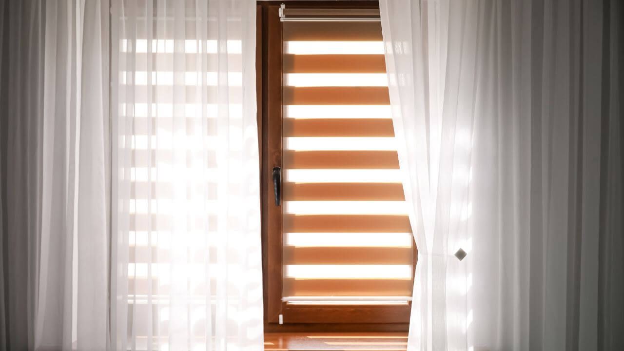 White curtains framing a window with sunlight streaming through.