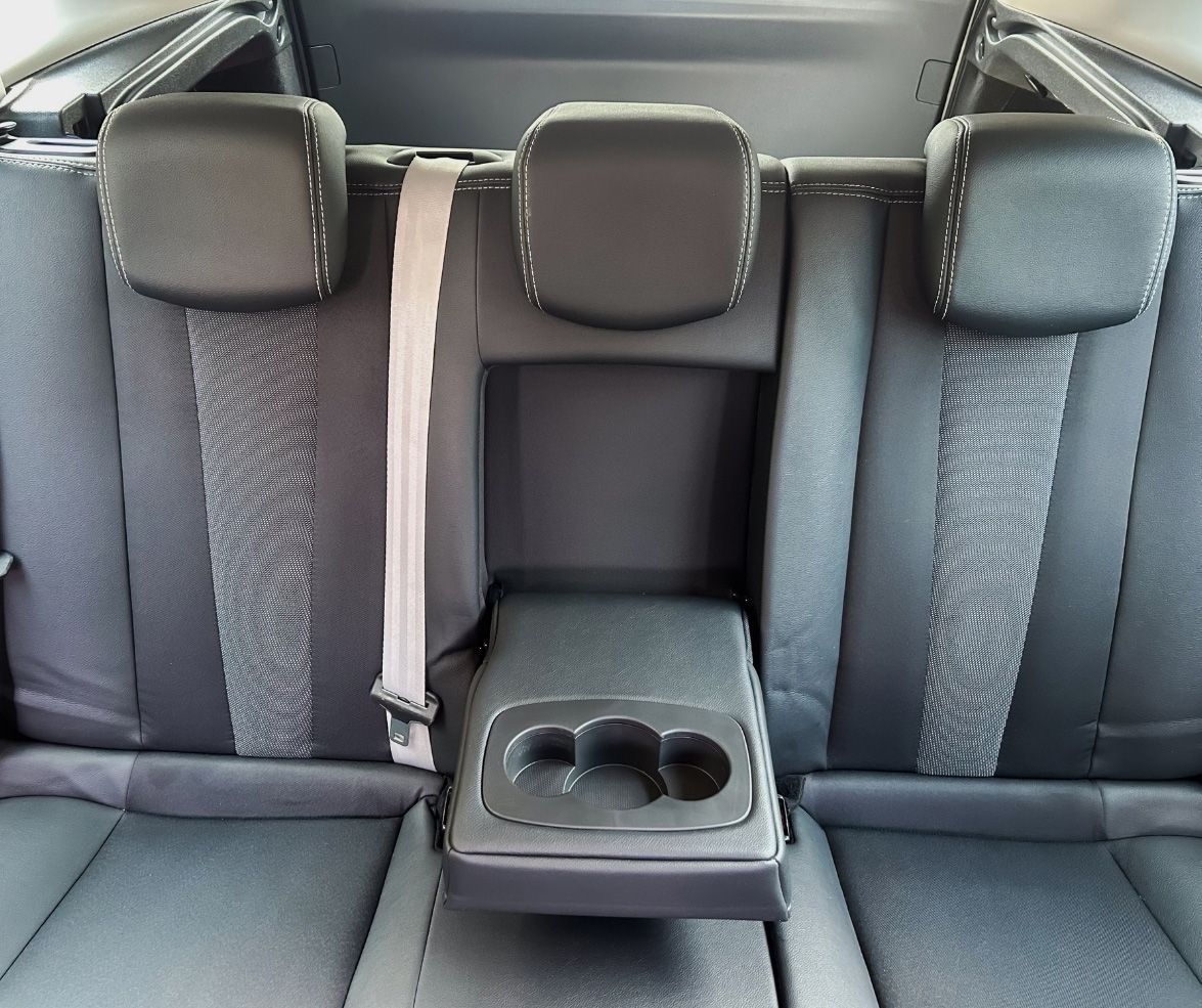 Car's rear seats with three headrests, center armrest with cup holders, and a seat belt