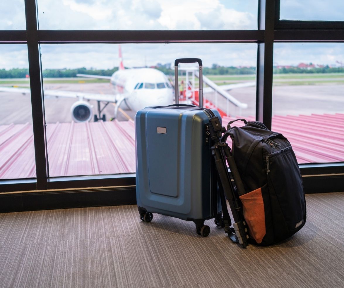 Blue suitcase and black backpack at an airport window