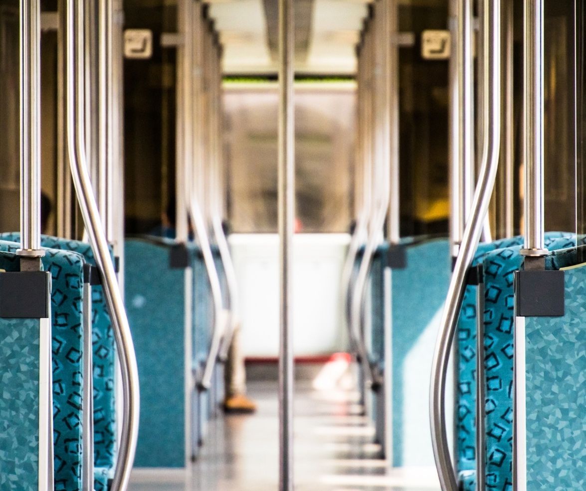 Interior of a mini bus with blue patterned seats, silver railings, and glass doors