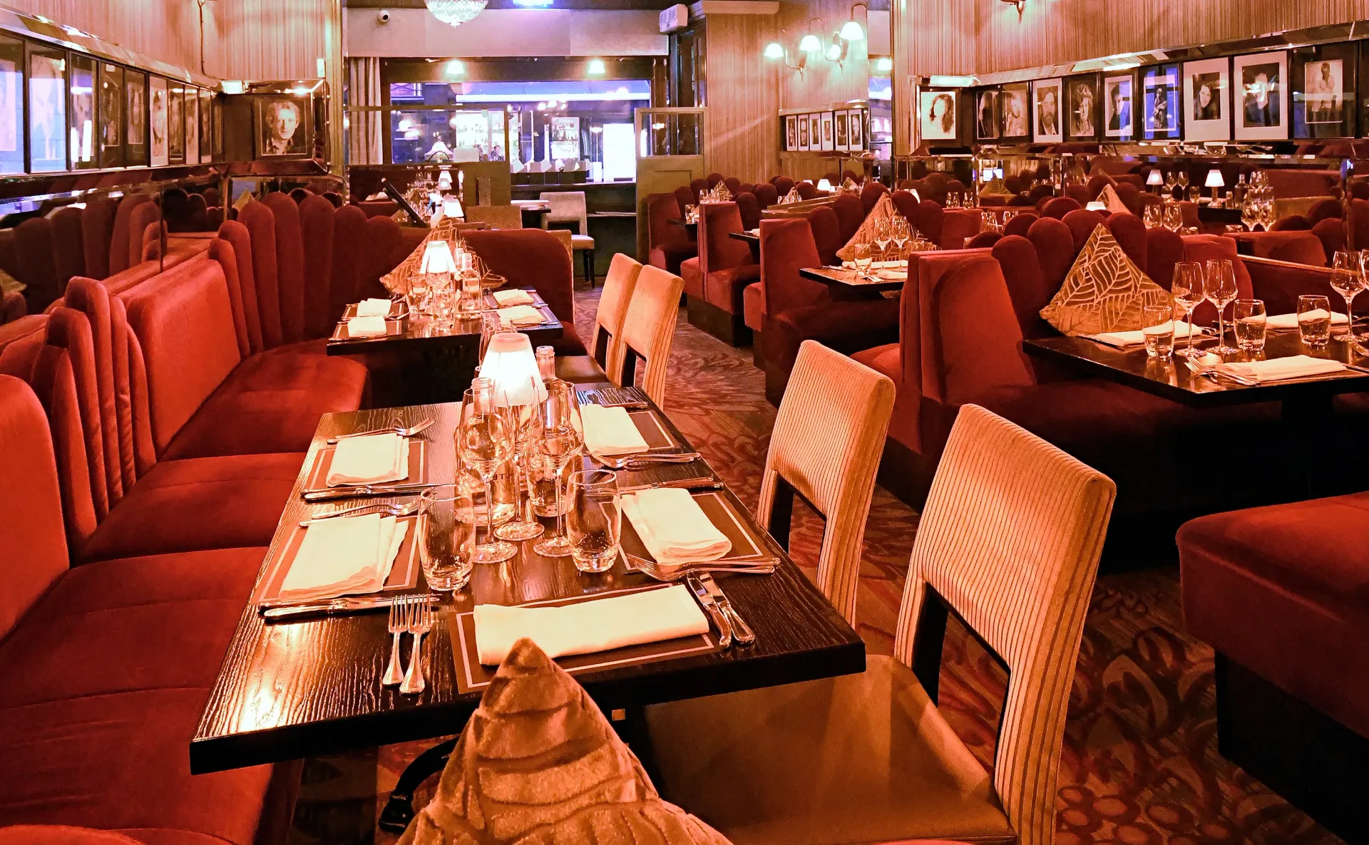 Elegant restaurant interior with red velvet booths and chairs, tables set for dining.