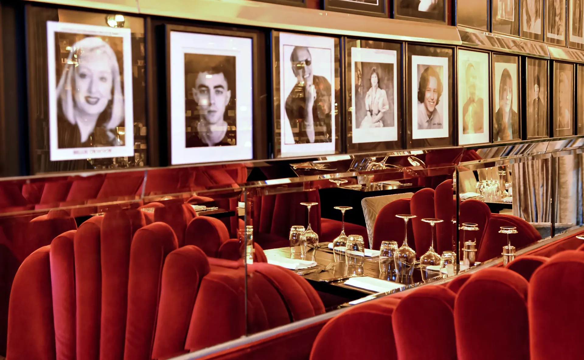 Red velvet booth seating reflects in a mirror; portraits line the wall above.