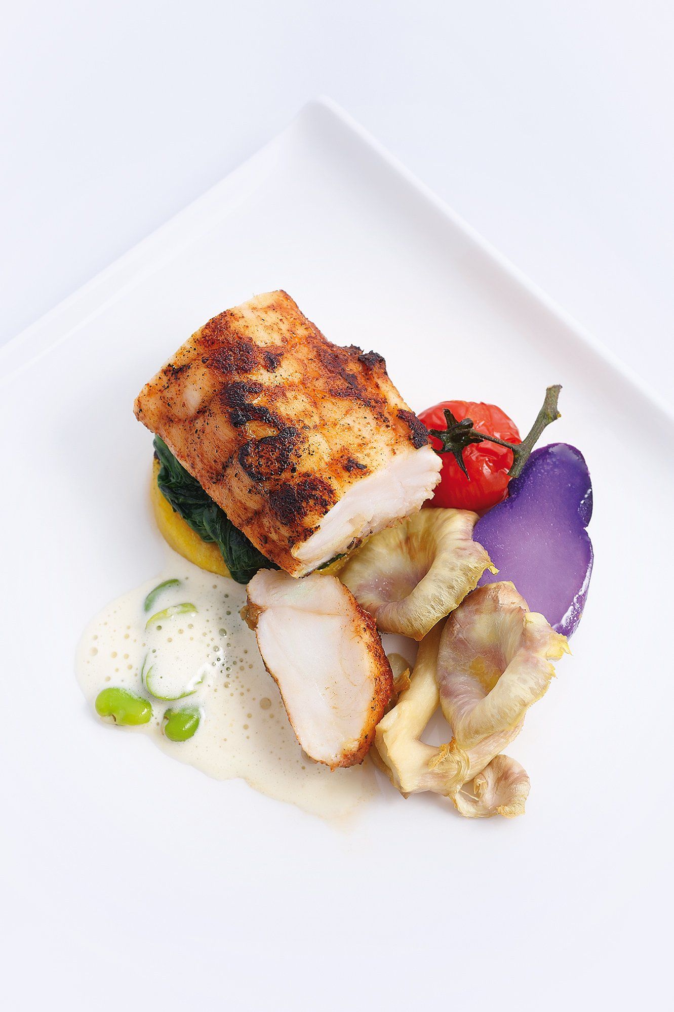 Grilled chicken breast with vegetables artfully arranged on a white plate.