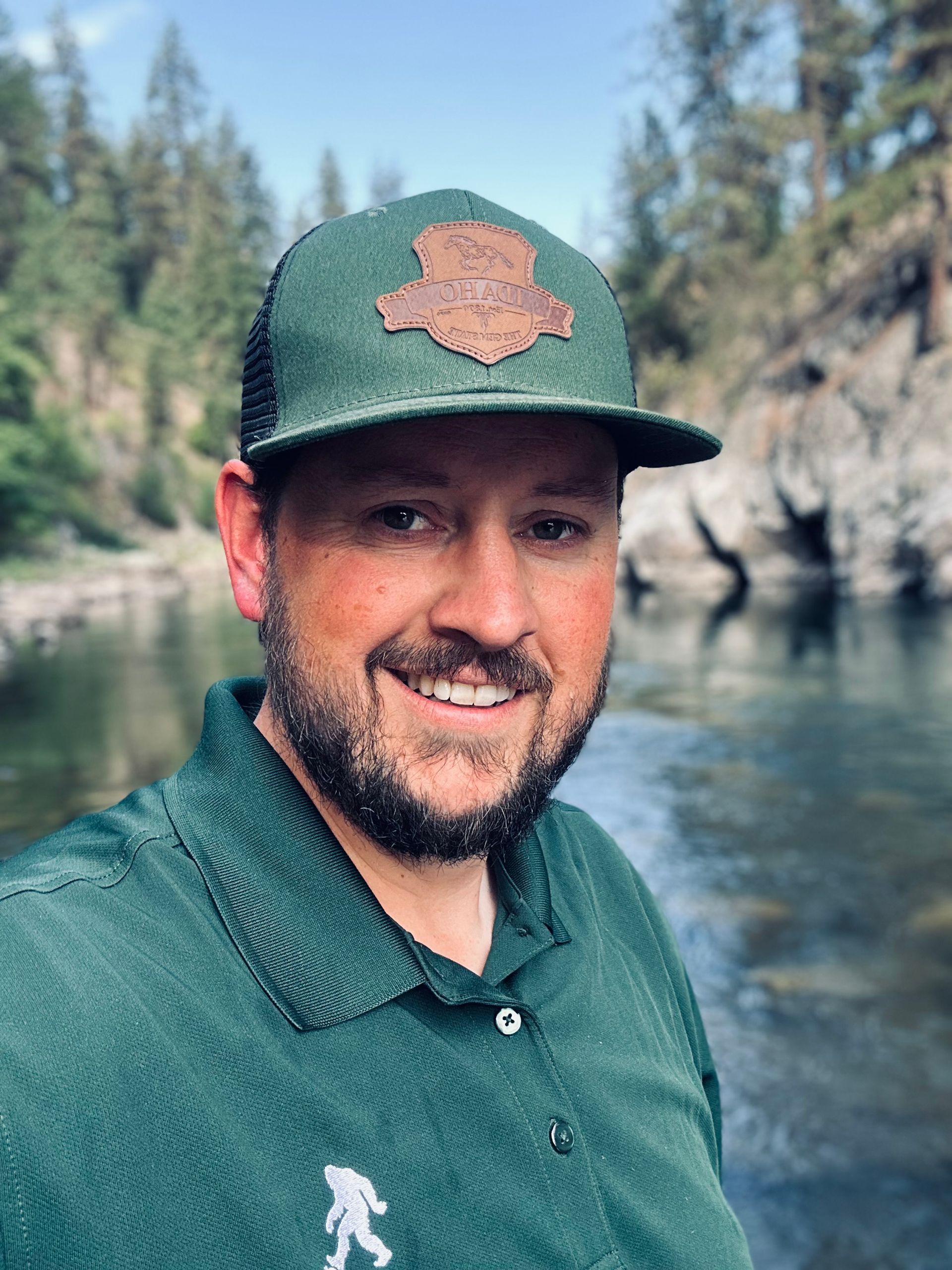 A man in a bigfoot costume is standing in front of a green background.