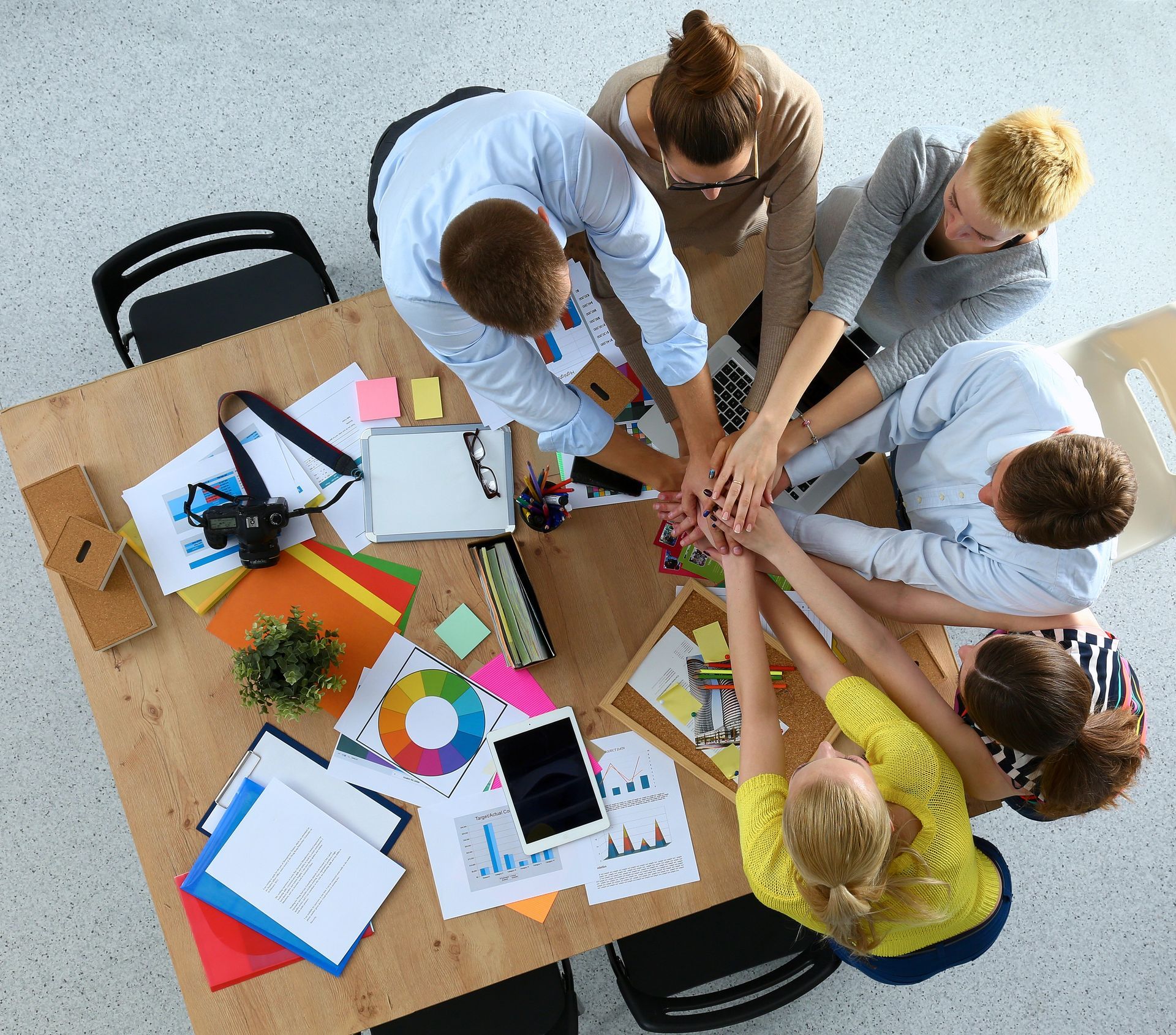 Un grupo de personas juntan sus manos en una mesa.