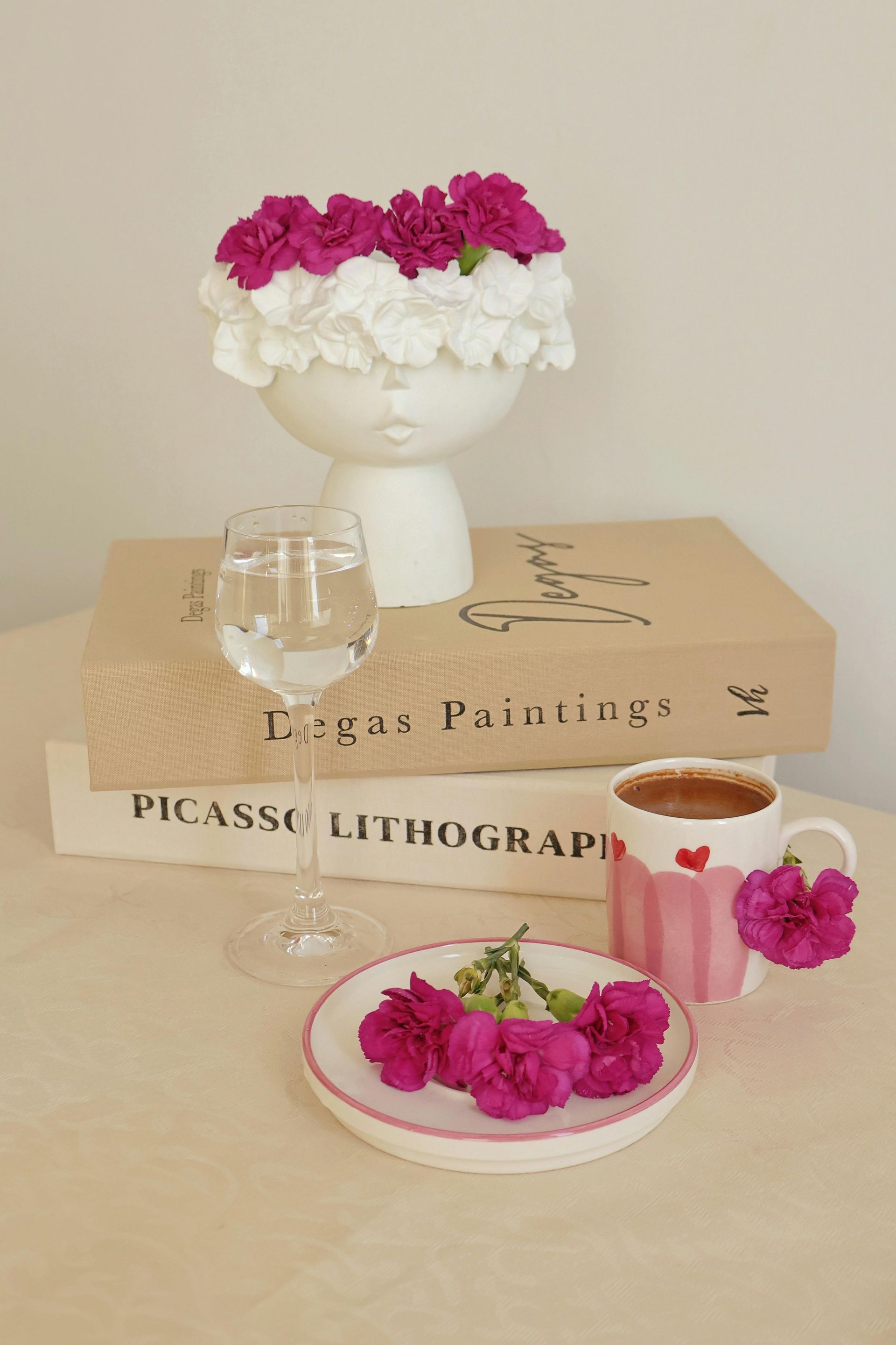 Una mesa con un jarrón de flores, una taza de café y un libro.
