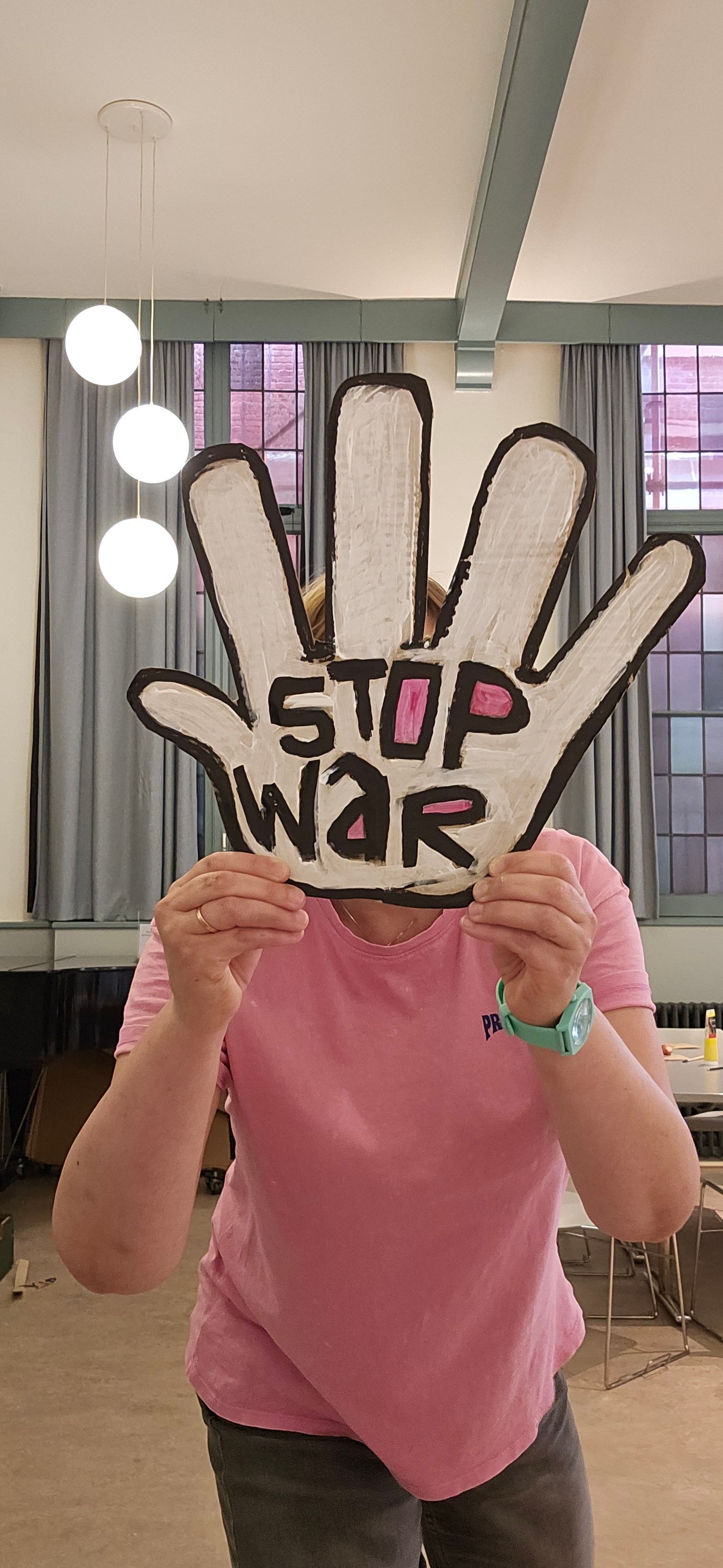 Een persoon houdt een handvormig bord vast met de tekst 