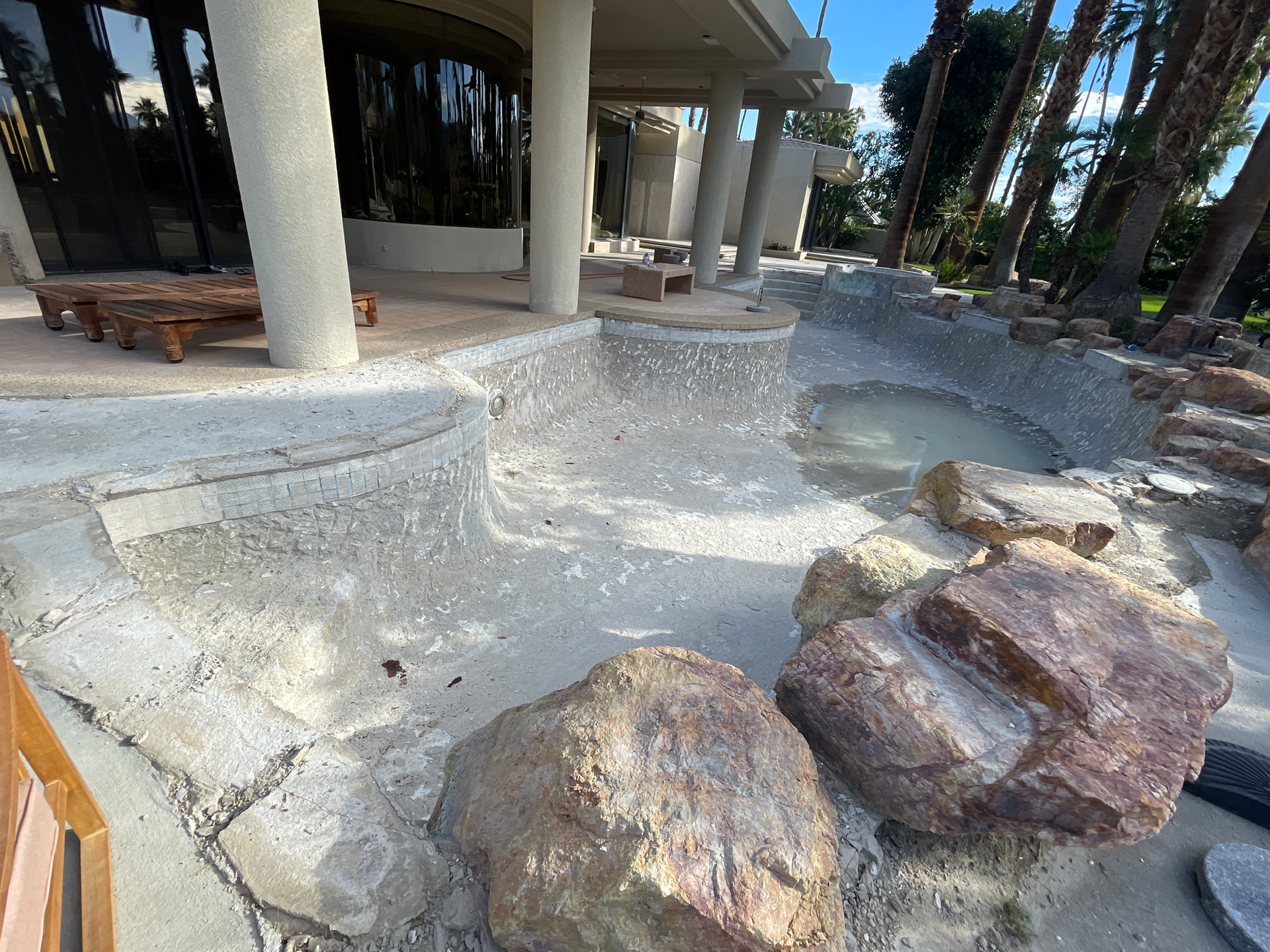 A large rock is sitting in front of a swimming pool.