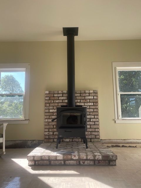 A wood stove is built into a brick fireplace in a living room