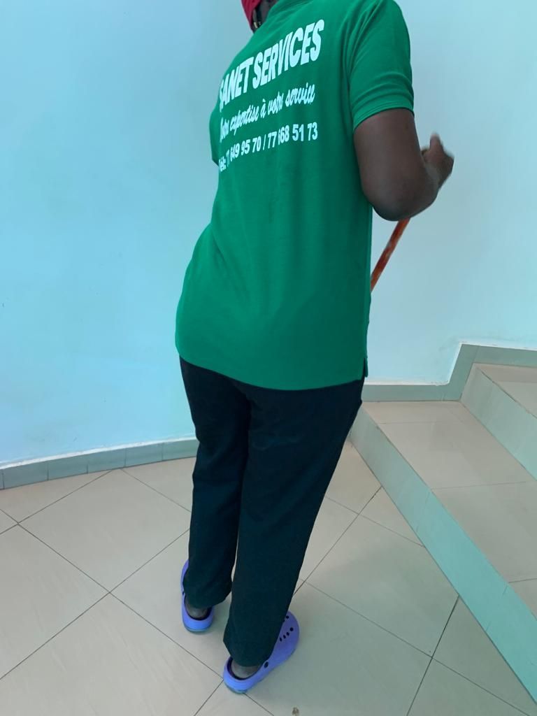 Une personne portant une chemise verte sur laquelle est écrit « services de nettoyage »