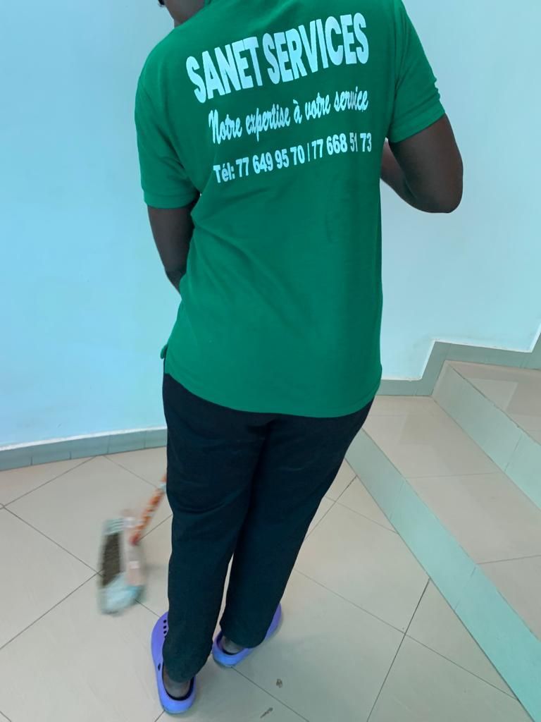 Un homme portant une chemise verte sur laquelle est écrit « Sanet Services »