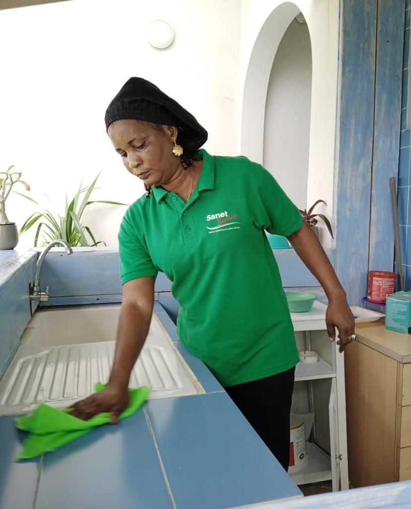 Une femme en chemise verte nettoie un comptoir de cuisine