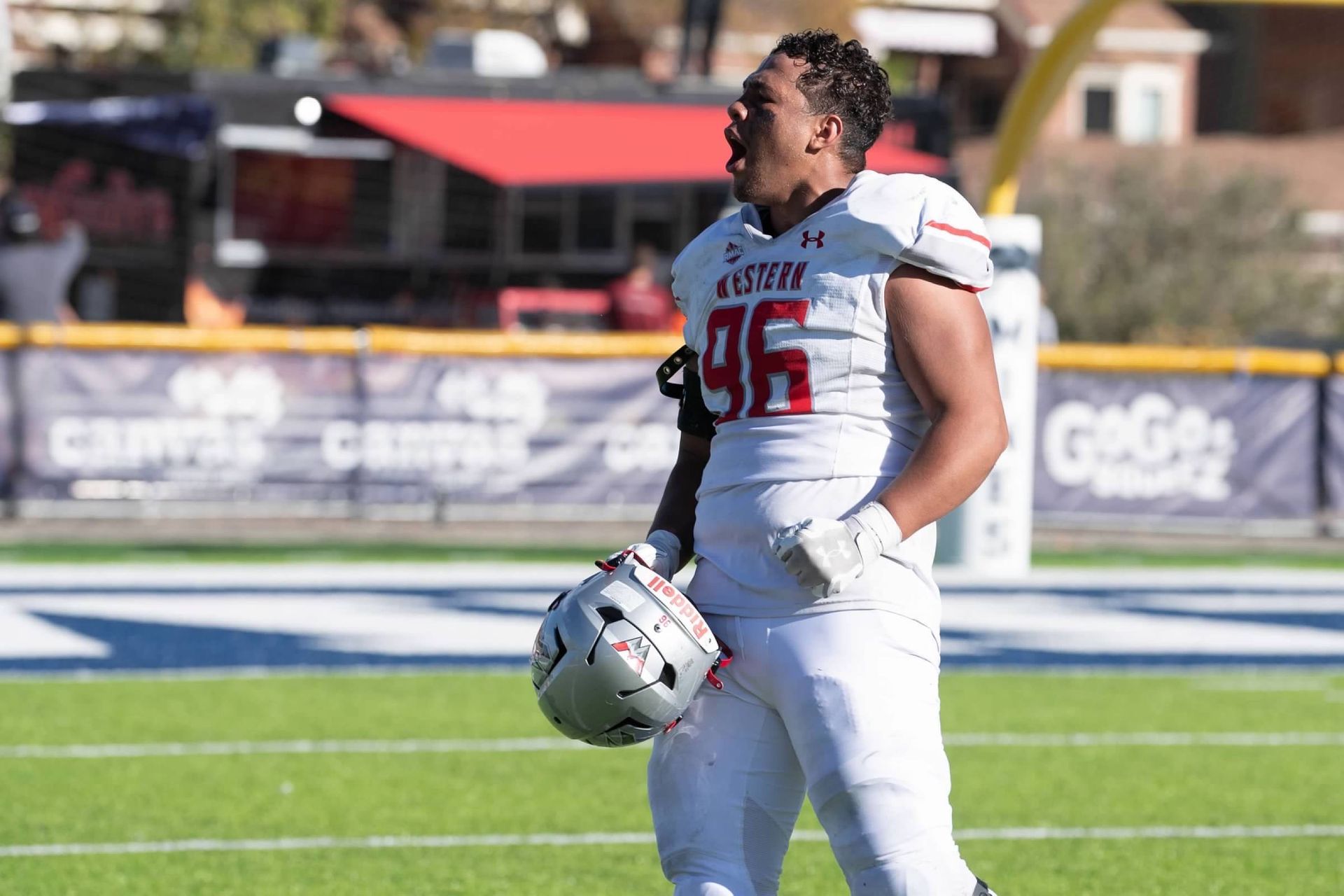 A football player is holding his helmet on the field.