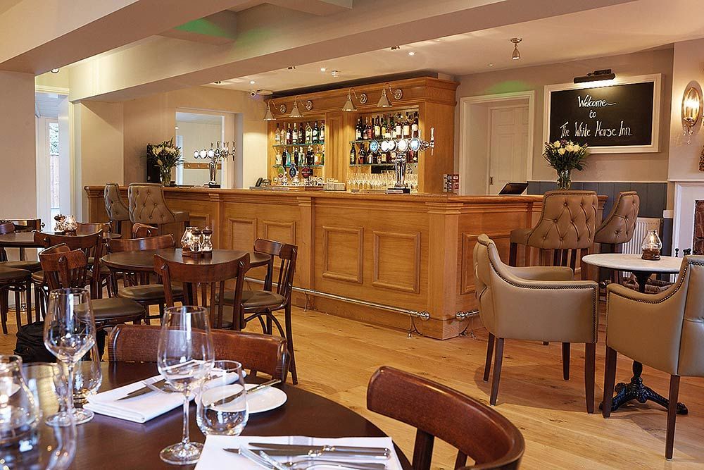 A restaurant with tables and chairs and a bar.