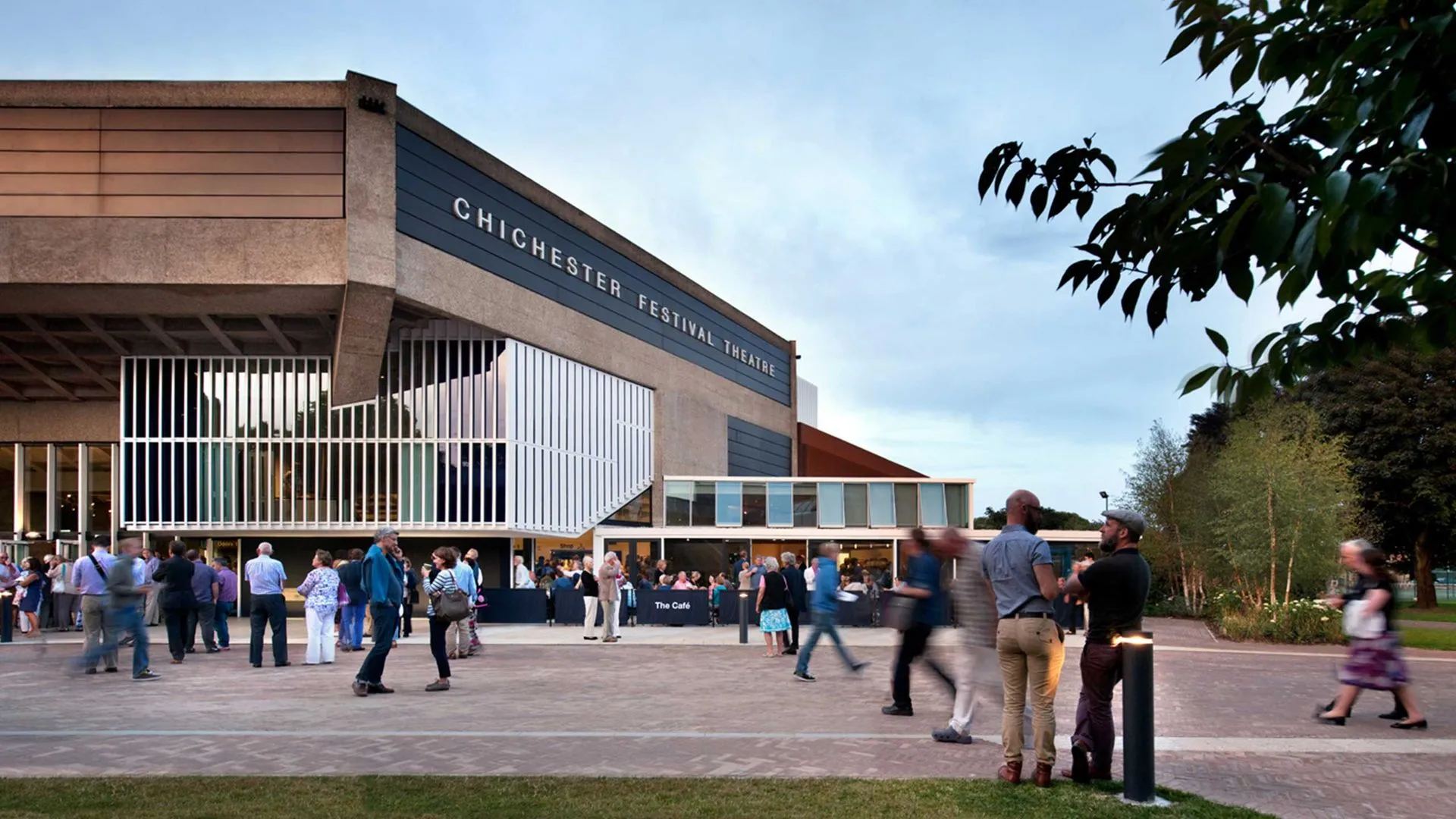 A group of people are walking in front of a large building that says ' ohio state university ' on it