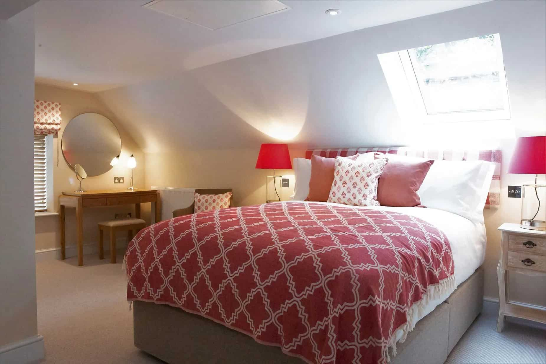 A bedroom with a bed , nightstand , mirror and lamps