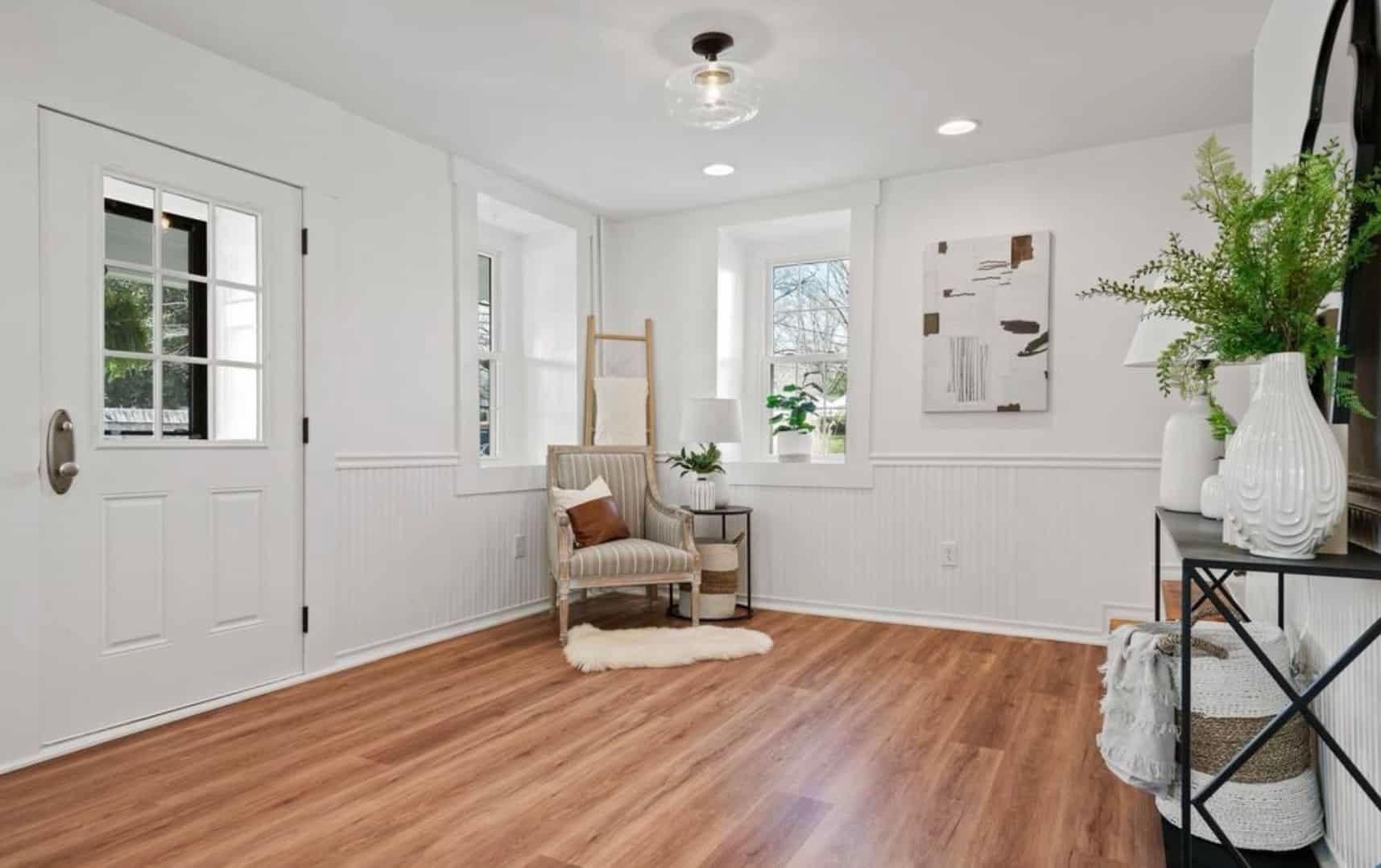A living room with hardwood floors , white walls and a chair.