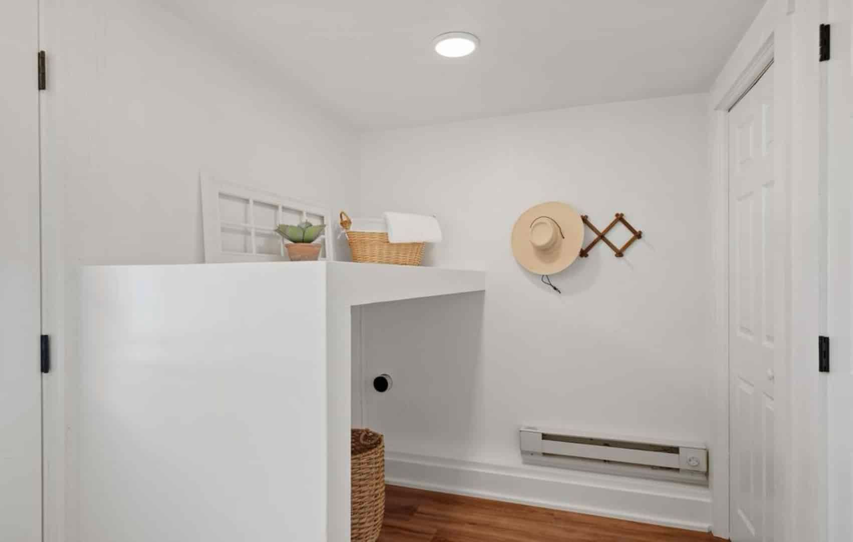 A laundry room with a washer and dryer and a hat hanging on the wall.