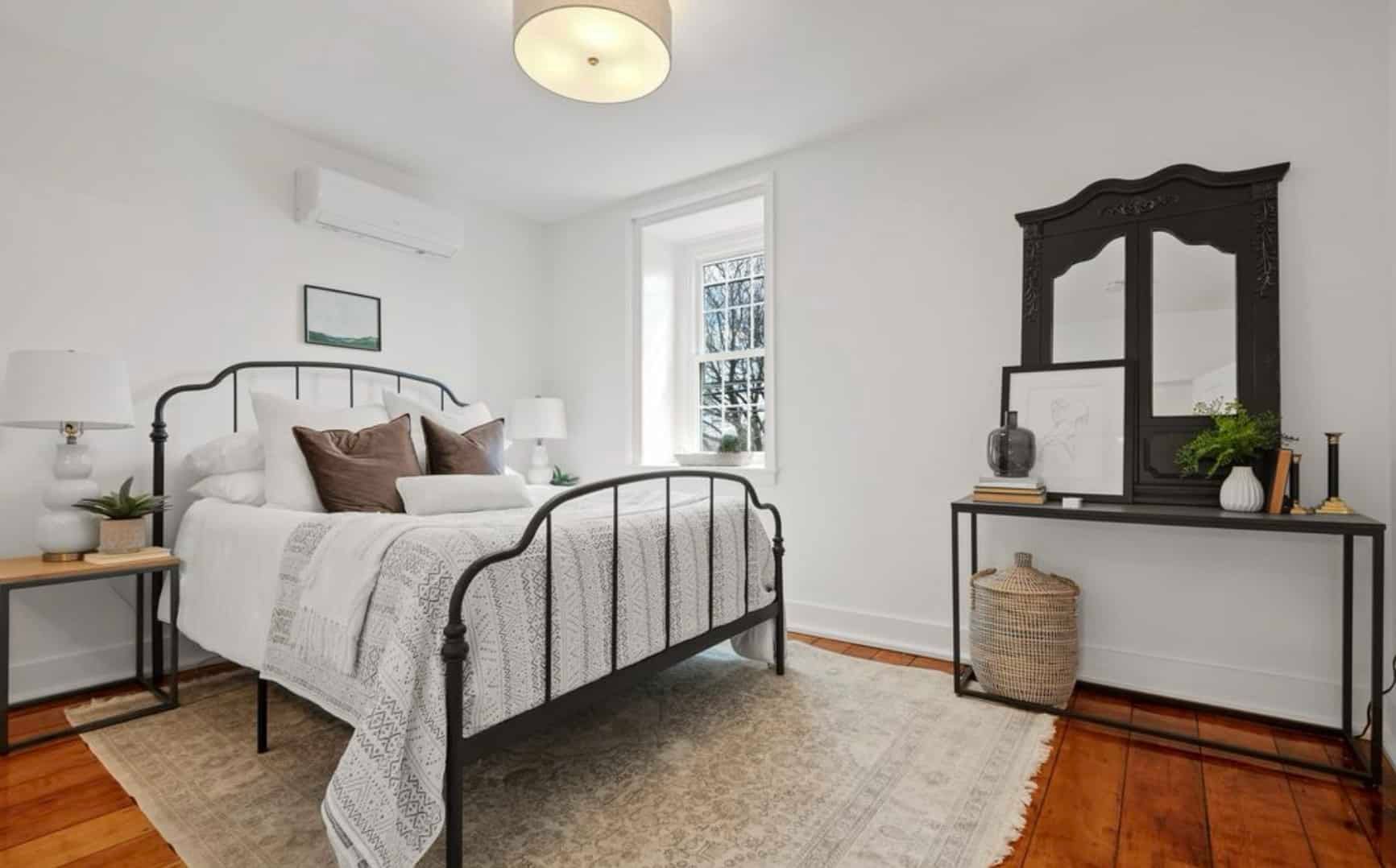 A bedroom with a bed , nightstand , and mirror.