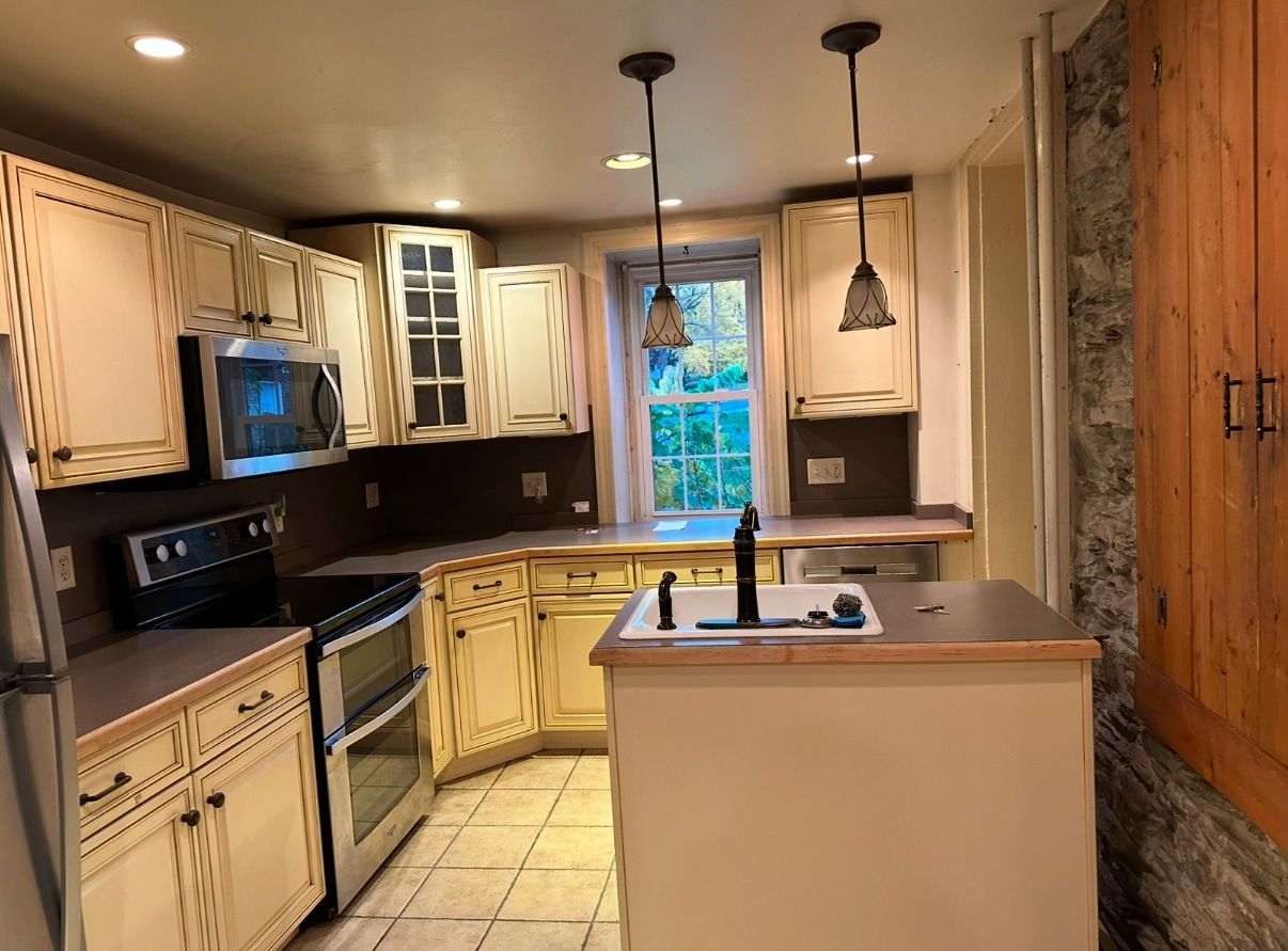 A kitchen with white cabinets , stainless steel appliances , a sink , and a window.