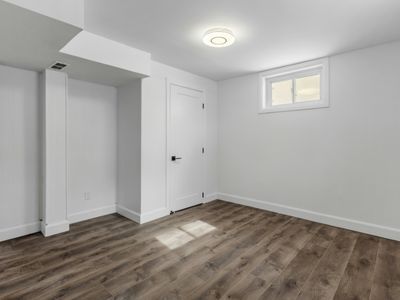 An empty room with hardwood floors , white walls and a window.