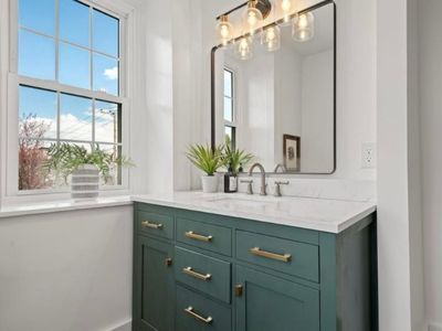 A bathroom with a sink , mirror and window.