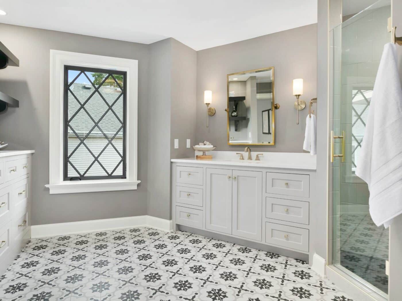 A bathroom with a sink , mirror , and window.