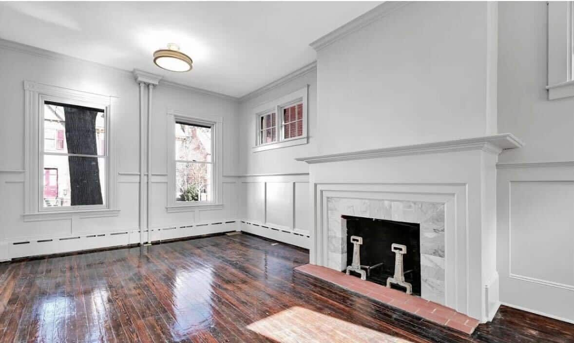 An empty living room with hardwood floors and a fireplace.