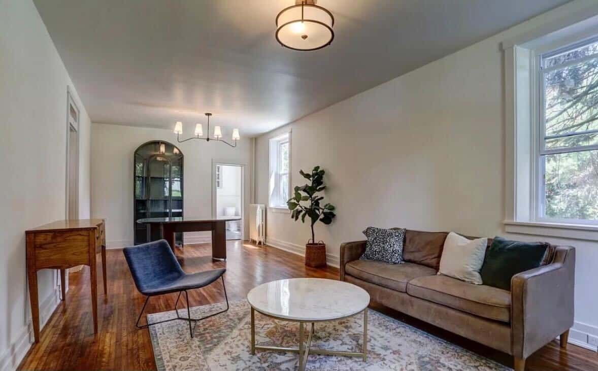 A living room with a couch , chair , table and window.