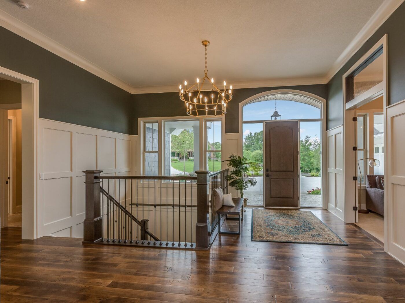 A large hallway with a staircase and a chandelier hanging from the ceiling.
