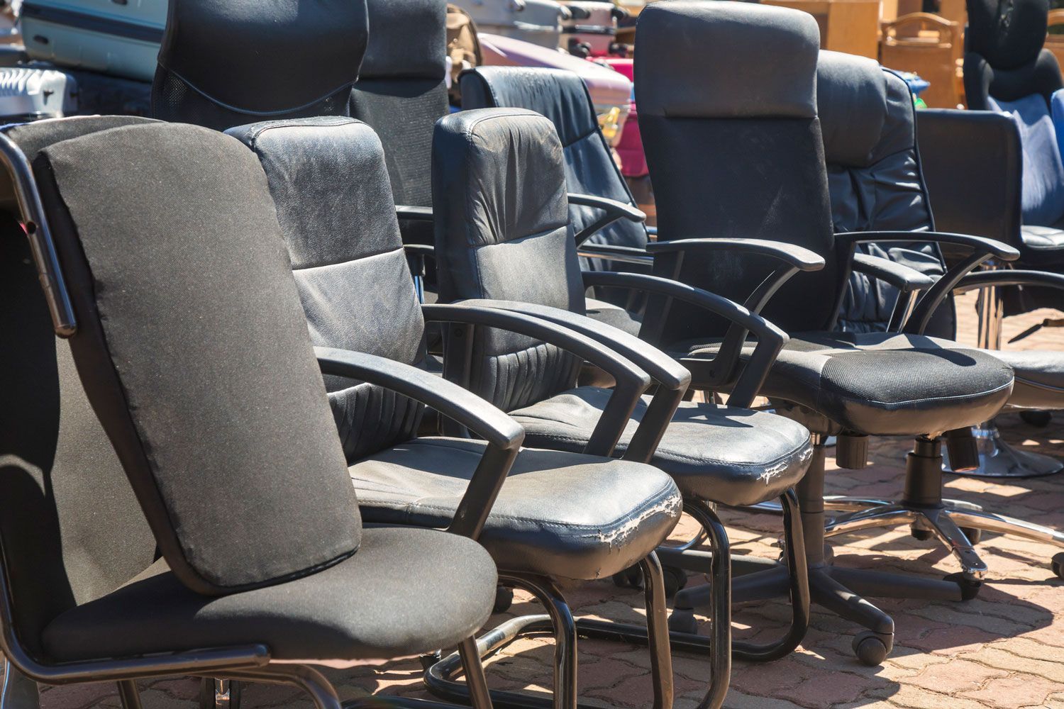 A row of black office chairs are sitting on a brick sidewalk.