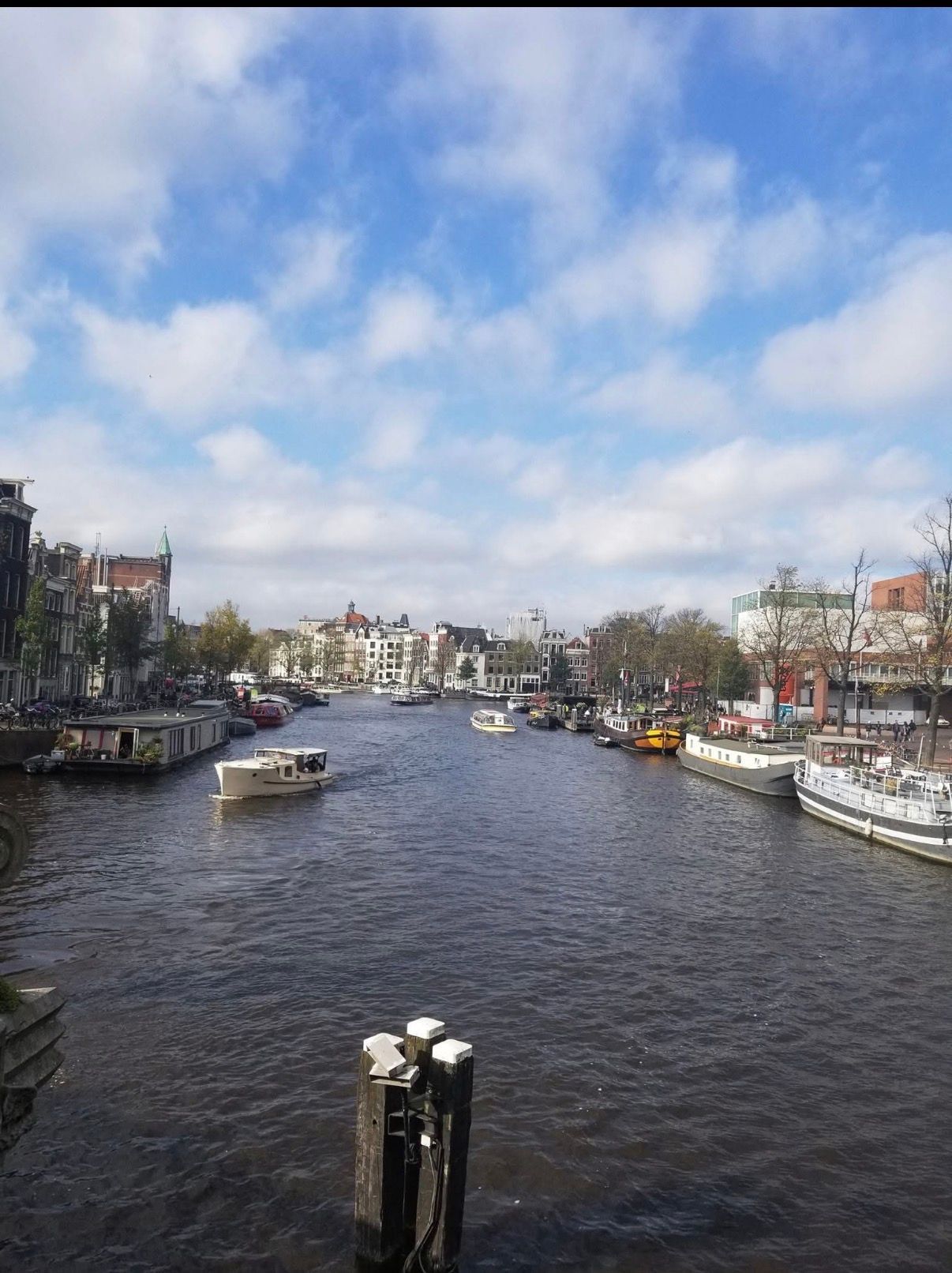 Canal lined with buildings and boats under a partly cloudy blue sky