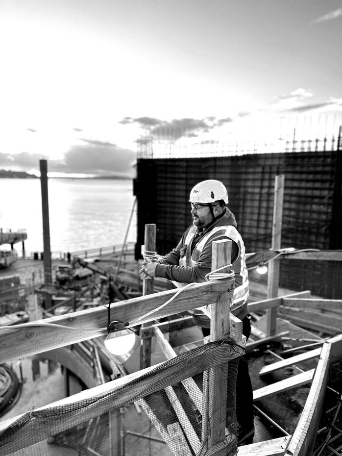 A black and white photo of a construction worker working on a structure.