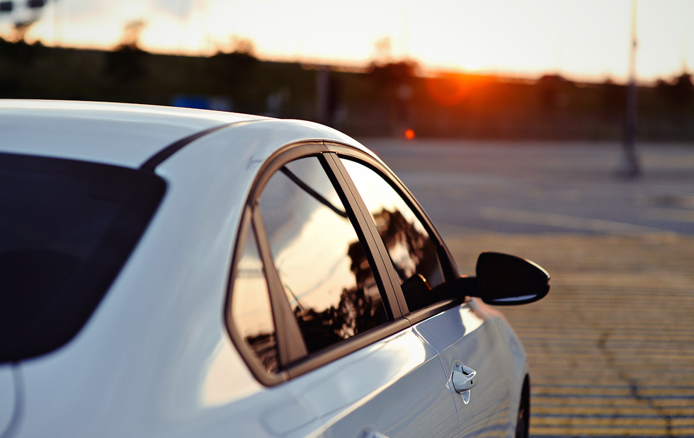A white car is parked in a parking lot at sunset.