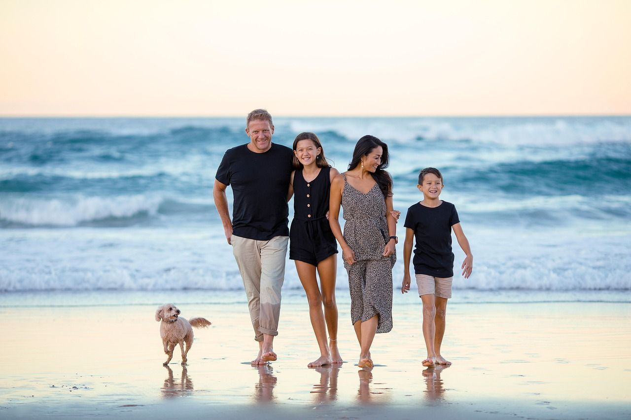 A family walking on the beach with their dog
