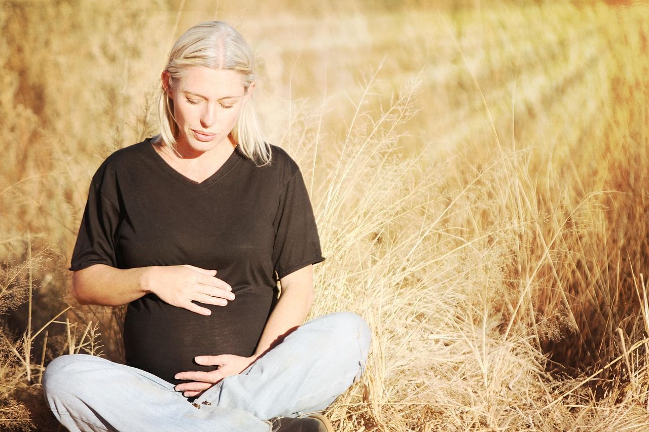 A pregnant woman sitting in a field