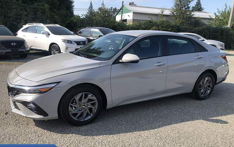 Gray Hyundai Elantra sedan parked on gravel in a car lot with other vehicles.