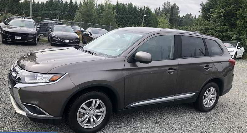 Brown Mitsubishi Outlander SUV in a car lot with other vehicles.
