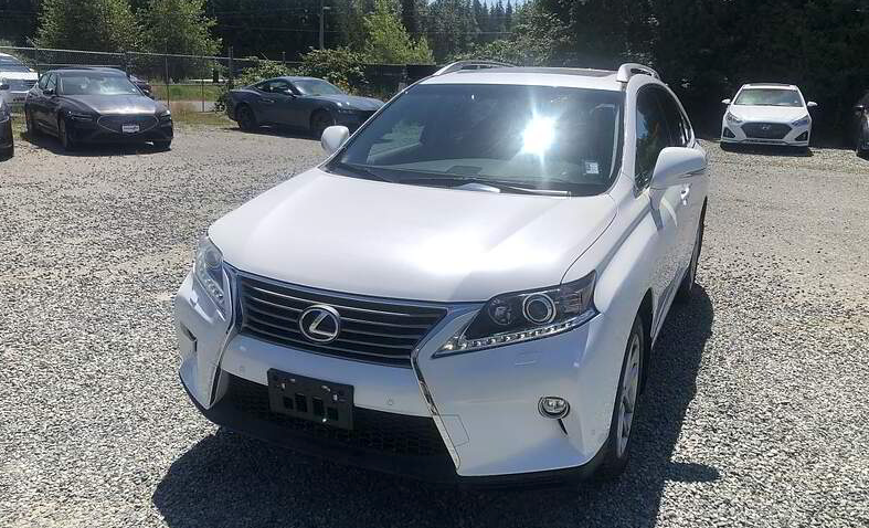 White Lexus SUV parked on gravel lot under sunny sky.