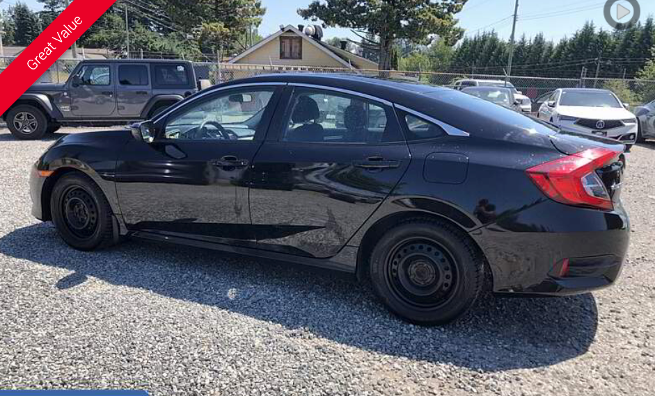 Black Honda Civic sedan parked outdoors on gravel.