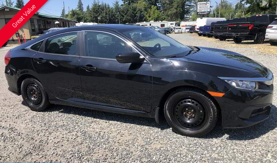 Black Honda Civic parked on gravel lot. 