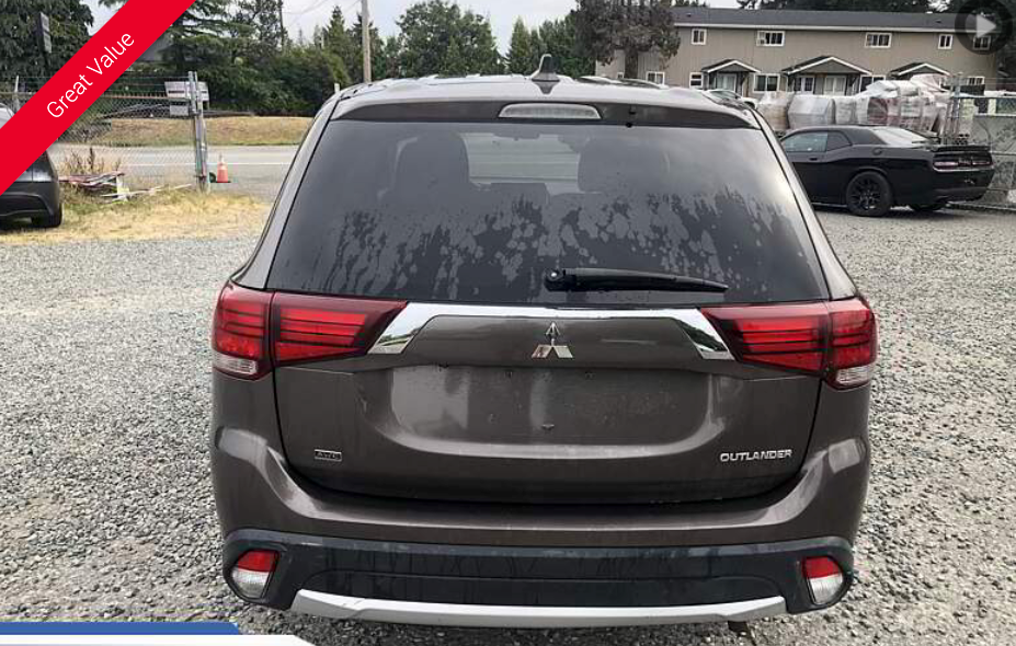 Rear view of a brown Mitsubishi SUV parked outside, overcast sky.