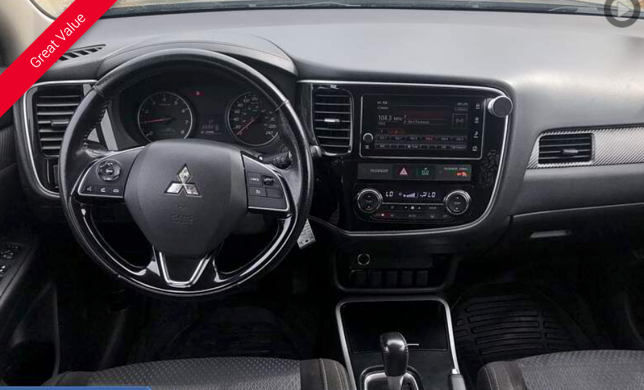 Dashboard of a Mitsubishi Outlander with black steering wheel, infotainment screen, and controls.