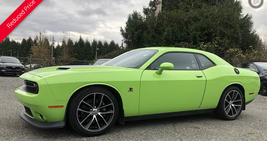 Green Dodge Challenger parked outdoors.