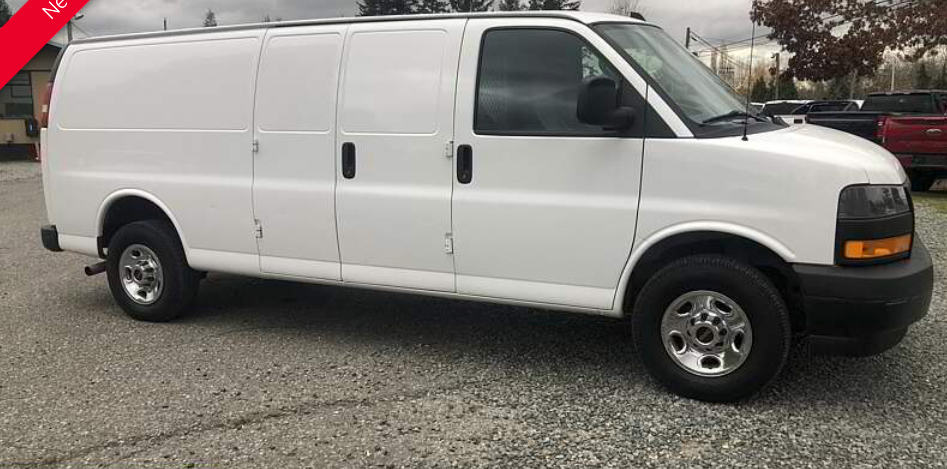 White cargo van parked on a gravel surface under an overcast sky.