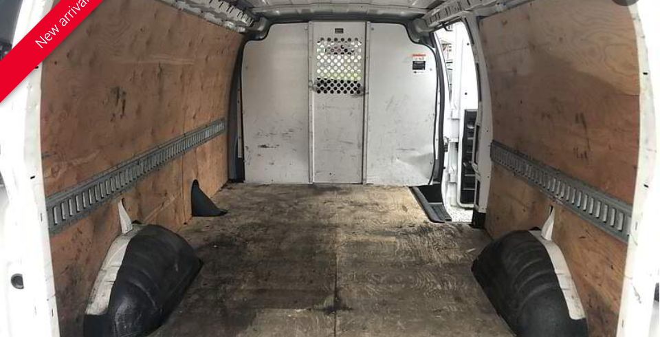Empty white cargo van interior with wood paneling and metal track.