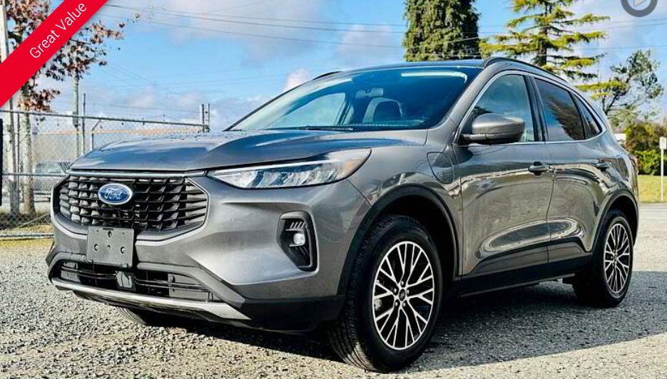 Gray Ford Escape SUV parked on gravel, front view. Blue Ford emblem, black and silver wheels, sunny outdoors.
