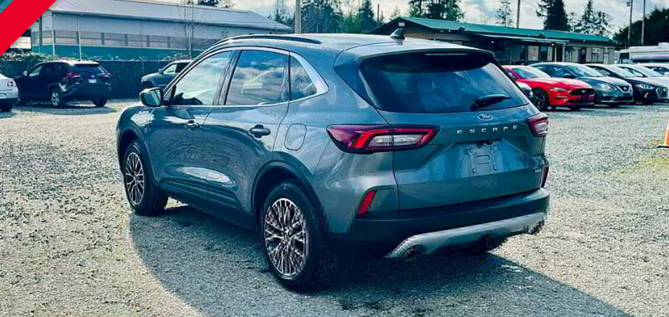 A gray SUV parked in a lot, other cars and buildings in the background. Sunny day.
