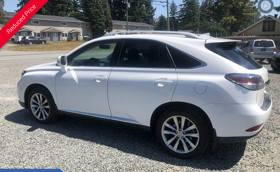 White Lexus SUV parked on gravel, with 